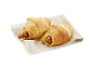 Deux croissants salés avec saucisse et graines de sésame sur un tissu en lin.