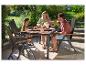 Famille mangeant en plein air à une table de jardin avec des chaises.