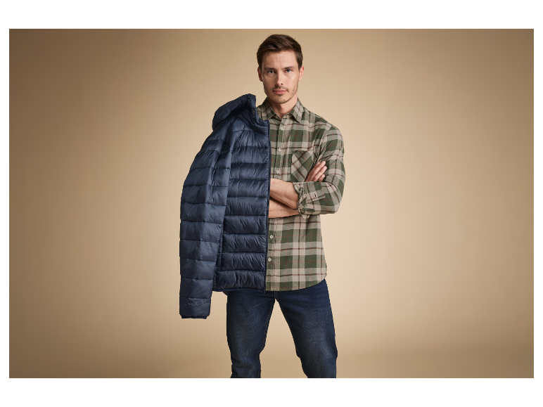 Modèle masculin portant une chemise à carreaux et une veste matelassée.