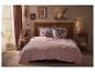 Une chambre douillette avec un lit rose, des oreillers fleuris et une décoration rustique.
