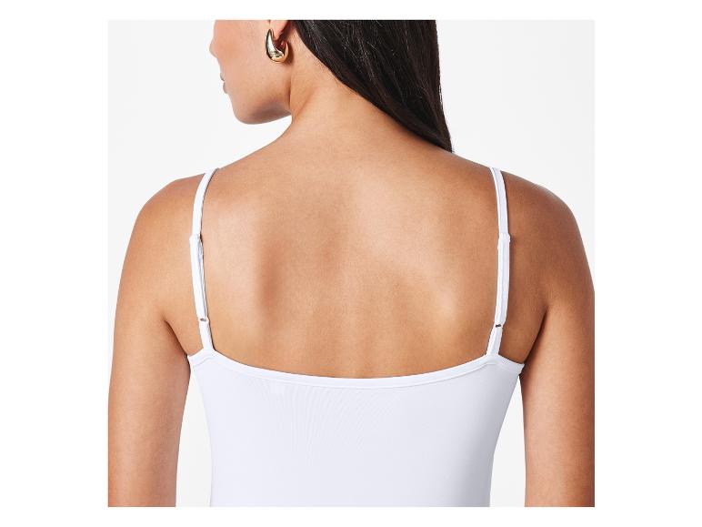 Haut blanc sans manches et boucles d'oreilles dorées.
