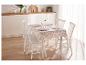 Table de cuisine blanche avec nappe fleurie et chaises blanches.