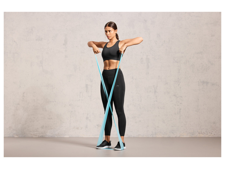 Une femme en tenue de sport fait des exercices avec un élastique de résistance.