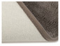 Un tapis de bain gris avec un dessous antidérapant.