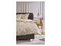 Chambre à coucher avec une parure de lit florale beige et une table de chevet en bois.