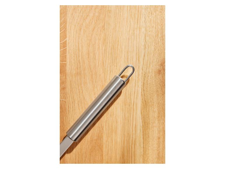 Ustensile de cuisine argenté sur surface en bois.