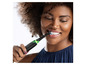 Une femme utilise une brosse à dents électrique Oral-B.