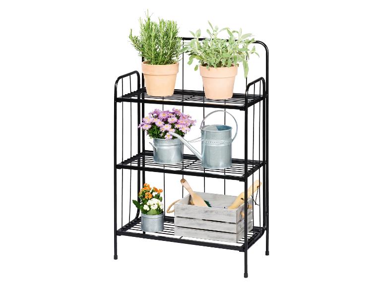 Étagère métallique noire à trois niveaux avec herbes, fleurs et outils de jardinage.