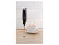 Mousseur à lait à côté d'une tasse de café avec de la mousse sur une surface en bois.