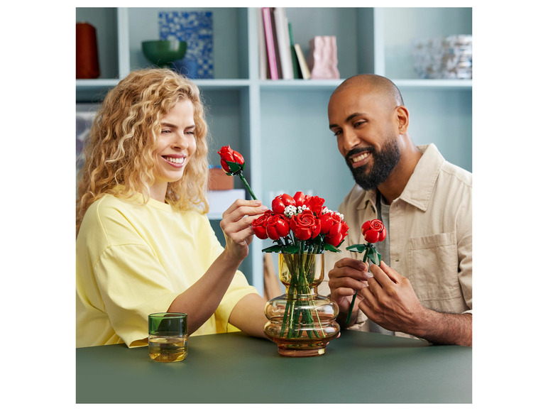 Un couple tient des roses LEGO dans un vase.