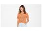 Femme en pull tricoté orange à manches courtes et short en jean clair.