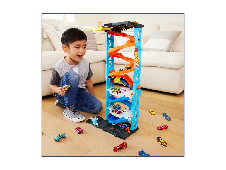 Garçon jouant avec une tour de stationnement Hot Wheels et des petites voitures.