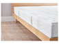 Un matelas blanc avec une texture ondulée sur un cadre de lit en bois.