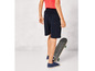 Un garçon portant un short bleu, des baskets et une planche à roulettes.