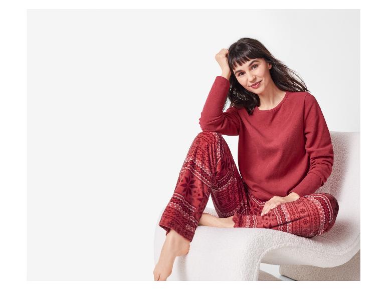 Femme en pyjama rouge à motifs, assise sur une chaise blanche.