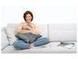 Une femme assise sur un canapé gris avec un coussin chauffant.