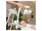 Parent ajustant une balancelle pour bébé avec un bébé allongé, regardant les jouets suspendus.