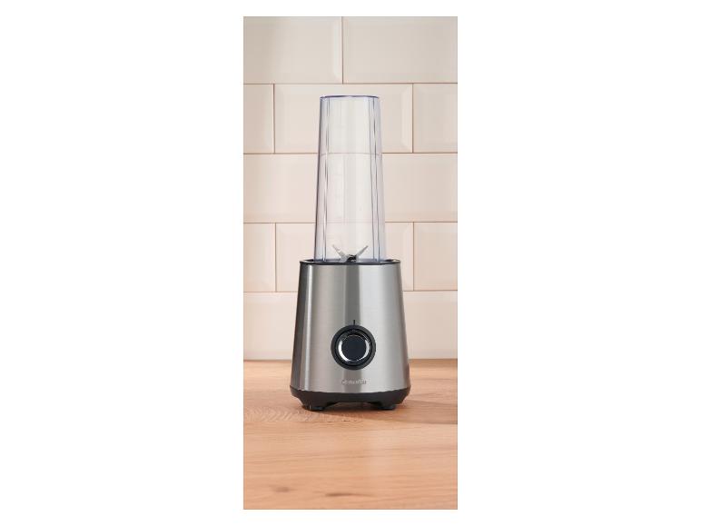 Mixeur en acier inoxydable avec récipient transparent sur un comptoir de cuisine en bois.