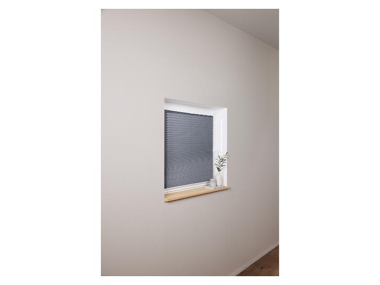 Stores plissés gris dans une pièce claire.
