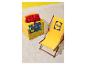 Chaise longue jaune avec logo et serviettes de plage à motifs sur un cube carrelé sur le sable.