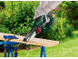 Une personne utilisant une tronçonneuse compacte Parkside pour couper une planche de bois.
