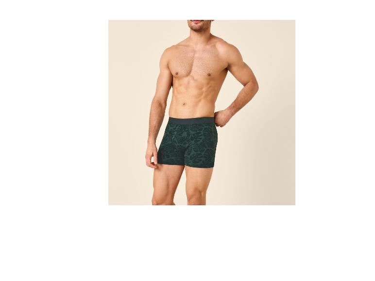 Homme torse nu posant en boxer vert à motif de feuilles.