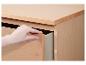 Main ouvrant le tiroir d'une commode en bois clair.