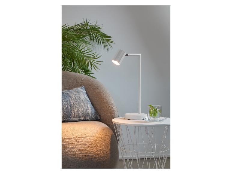Lampe de bureau blanche moderne à côté d'un fauteuil confortable.