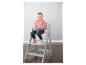 Une petite fille assise sur une chaise haute Stokke Tripp Trapp grise.