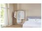 Housses de vêtements et portant dans une chambre avec un lit et une fenêtre.