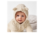Adorable bébé dans une combinaison en peluche beige.