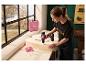 Une femme perce une lettre en bois avec la perceuse-visseuse sans fil rose PARKSIDE 20 V.