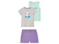 Un ensemble comprenant un t-shirt gris avec un imprimé de palmiers, un débardeur vert menthe avec l'inscription 'Tropical Vibes' et un short violet.