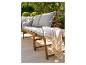 Banc de jardin en bois avec coussins gris et plaid, sur une terrasse ensoleillée.