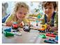 Deux enfants jouent avec des voitures de course LEGO Duplo sur le sol.