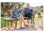 Un couple assis sur un banc en bois avec des coussins dans le jardin.