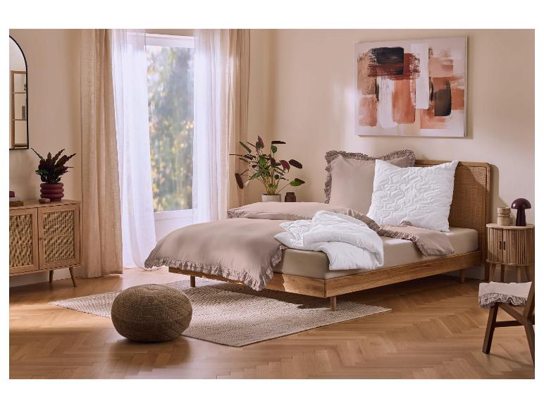 Chambre avec parure de lit beige à volants, lit et table de chevet en bois, et un tableau.