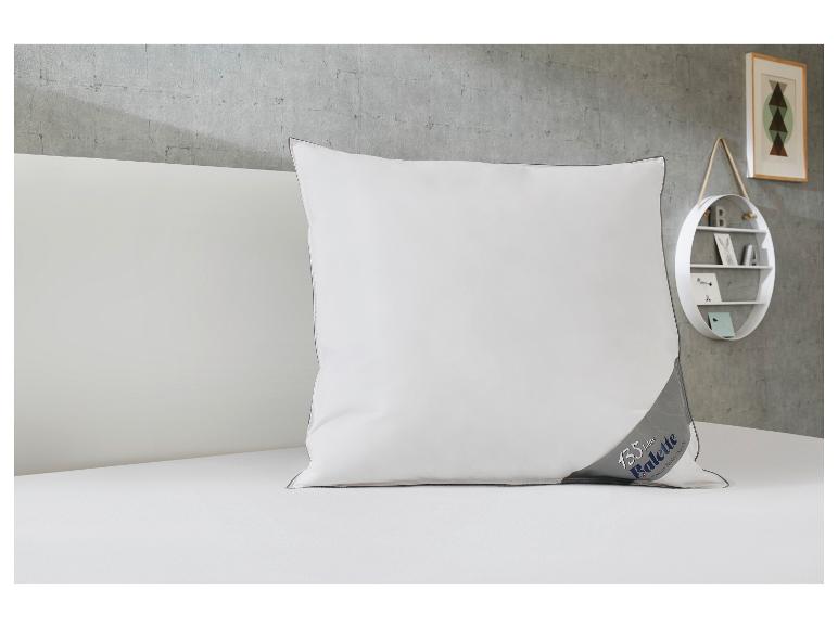 Oreiller blanc avec bordure grise et logo '135 Jahre Balette' sur un lit blanc.