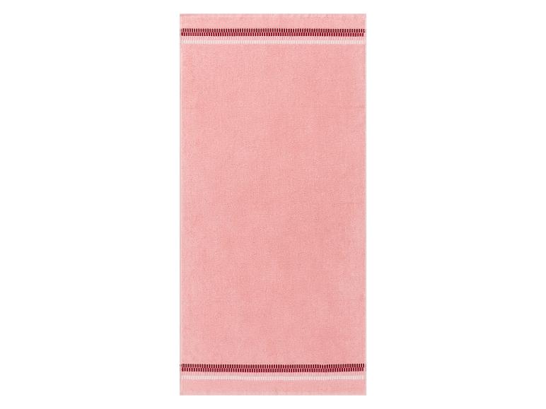 Une serviette de bain rose avec des bordures rouges et blanches.