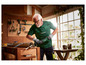 Un homme utilise une scie Parkside pour couper un tuyau dans un atelier.