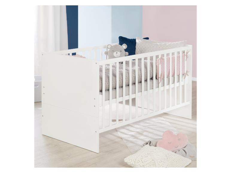 Lit bébé blanc avec literie grise et coussins décoratifs, dans une chambre aux murs bicolores.