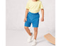 Un garçon porte un short bleu et des baskets blanches.