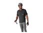 Homme en casque, maillot et cuissard de cyclisme tenant des lunettes de soleil.