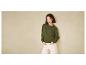Une femme portant un pull vert et un pantalon blanc