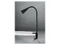 Une lampe de lecture flexible noire avec une pince fixée sur une table blanche.