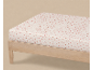 Drap-housse à petit motif floral rose sur un cadre de lit en bois clair.