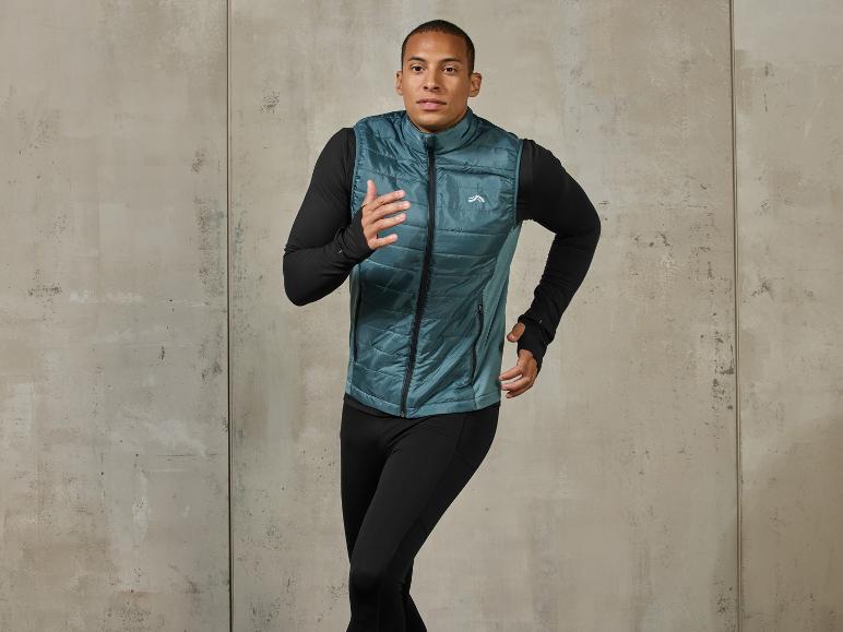 Un homme porte un gilet bleu Craft et un pantalon de jogging noir.