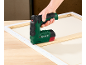 Main utilisant une agrafeuse électrique Parkside pour tendre une toile sur un cadre en bois.