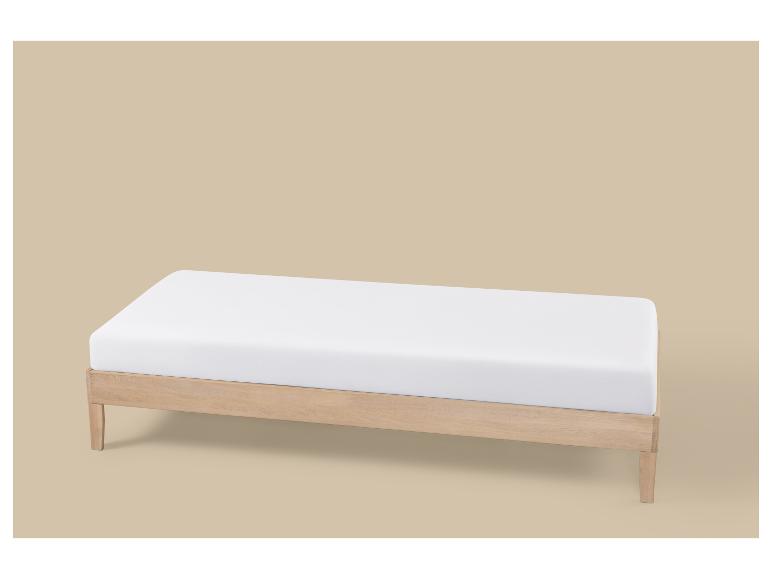 Sommier en bois clair avec matelas blanc sur fond beige