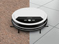 Un aspirateur robot blanc Silvercrest sur un tapis et des carreaux.